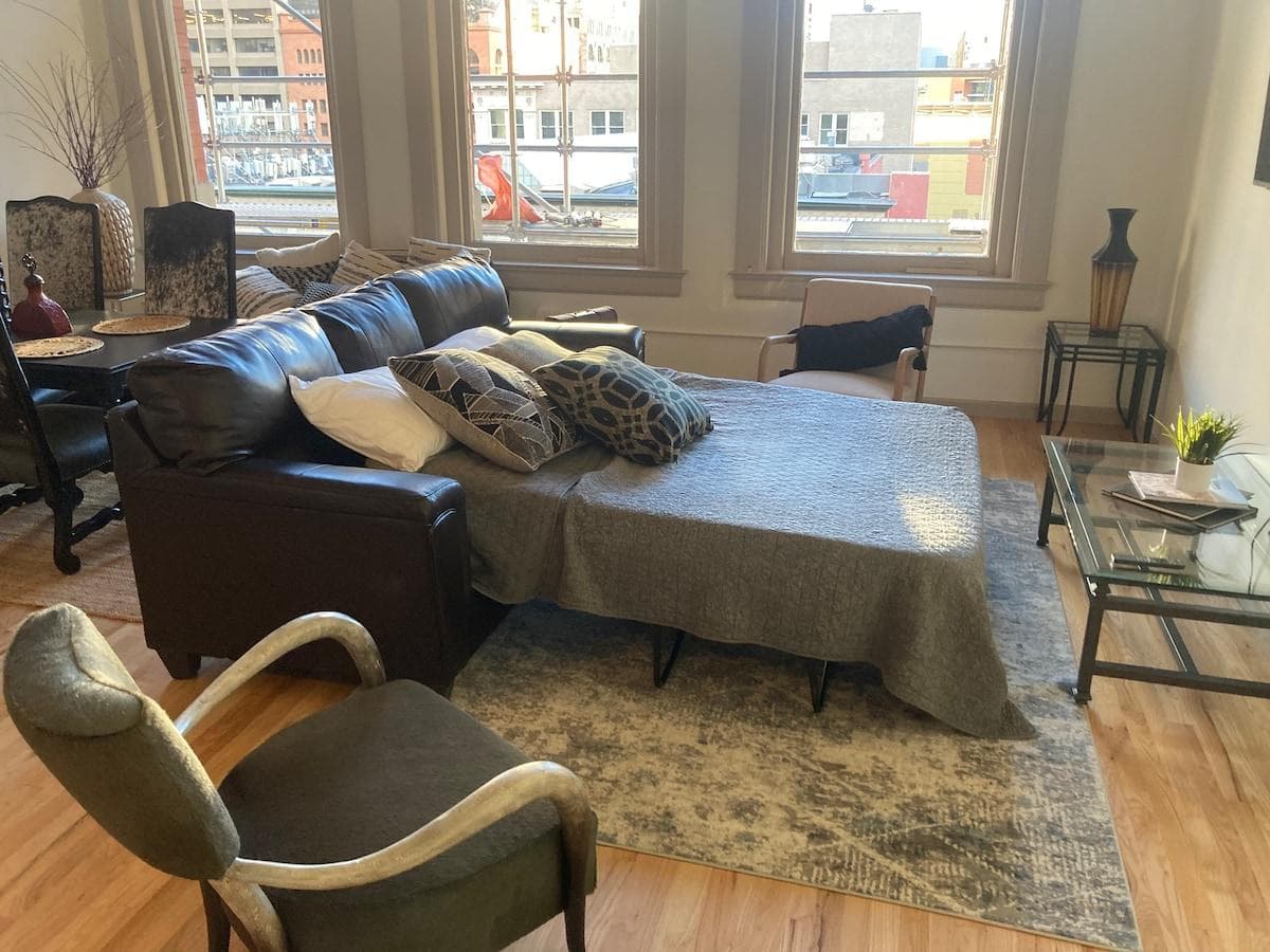 Sofa bed in the living room with queen-size mattress, blankets, pillows