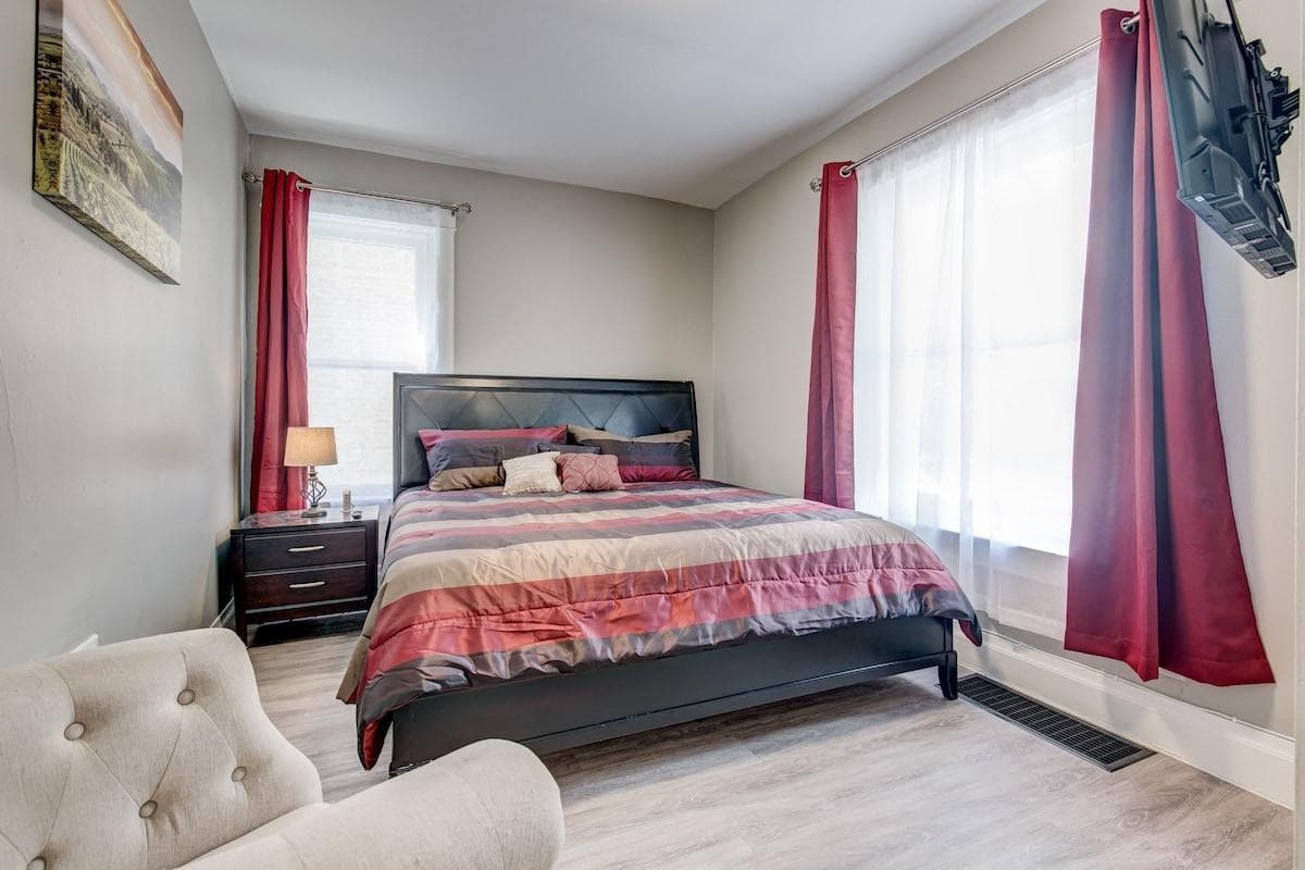 One bedroom featuring a king-sized bed with a brand new hybrid memory foam mattress, smart TV, and bedside table with storage.